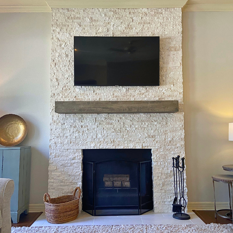 White stacked stone fireplace with minimalist mantel in a modern living room.