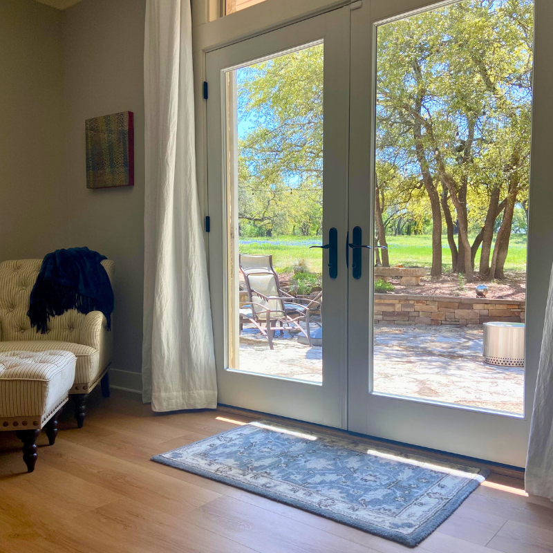 Light wood luxury vinyl in a master bedroom nook with French doors opening to a scenic outdoor space.