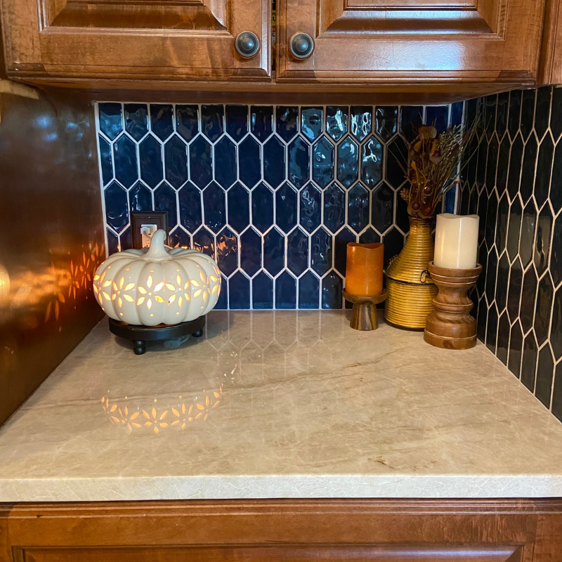 Dark blue picket-shaped backsplash with fall decor.