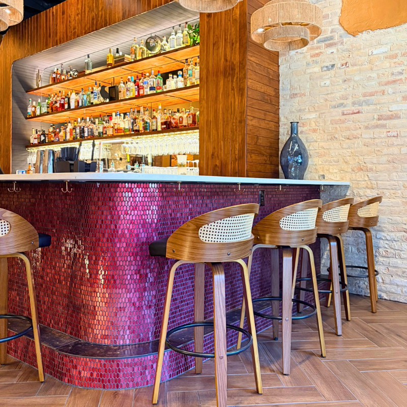 Glossy, red tile installed as the backsplash at a bar with eclectic, modern design.