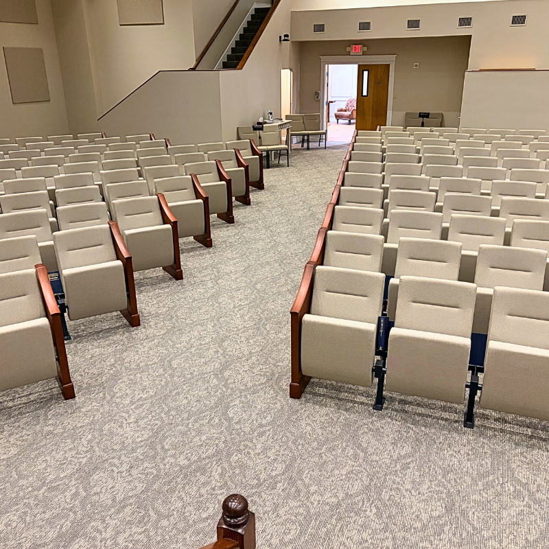 Church stadium seating in a large sanctuary with damask-patterned commercial carpet.