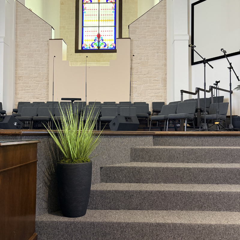 Gray commercial carpet on the steps of a church sanctuary with a stained glass window.