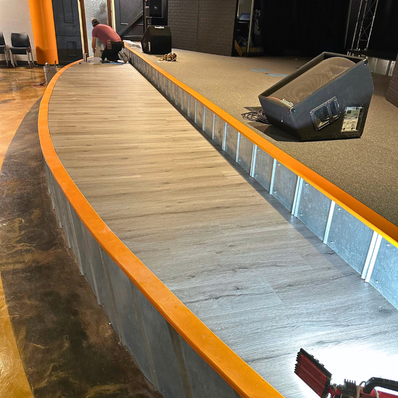 Gray luxury vinyl being installed on church youth group's small stage.