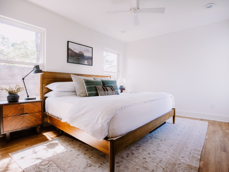 Modern, minimalist, light bedroom with area rug and hardwood floors